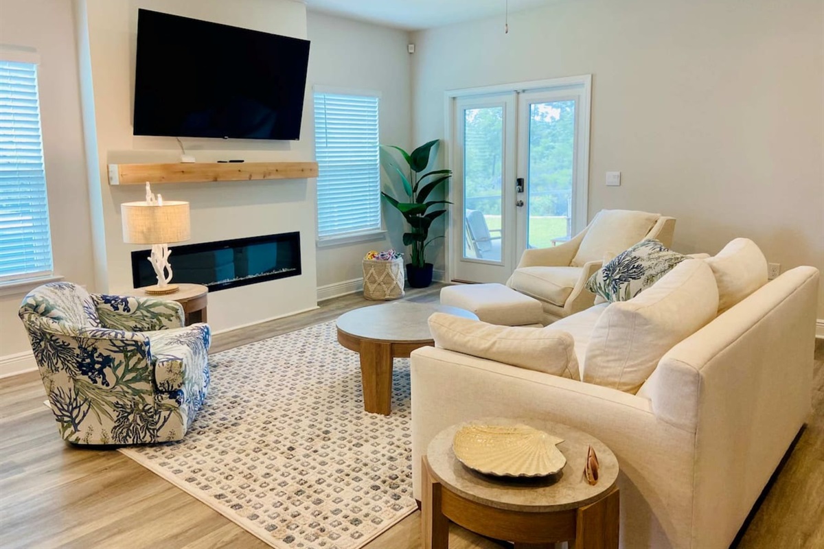 Spacious living area with comfy seating, an electric fireplace, and 70” Roku TV—ideal for movie nights after beach days. 