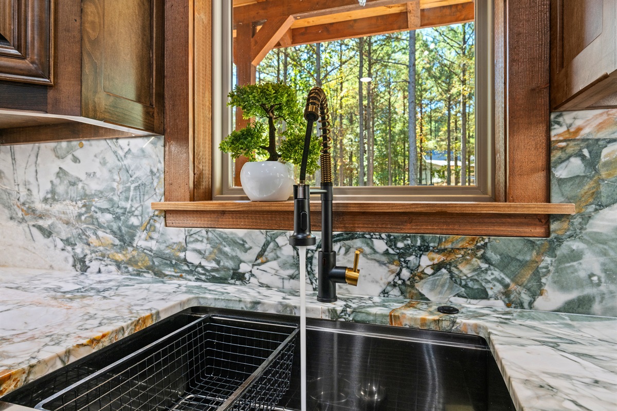 Large farmhouse sink and scenic kitchen window views.