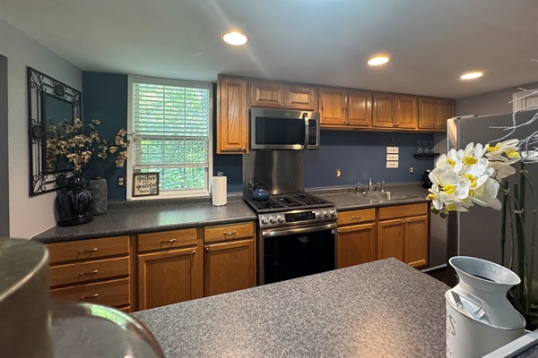 Expanded view of the kitchen area with stove and microwave and counter space.