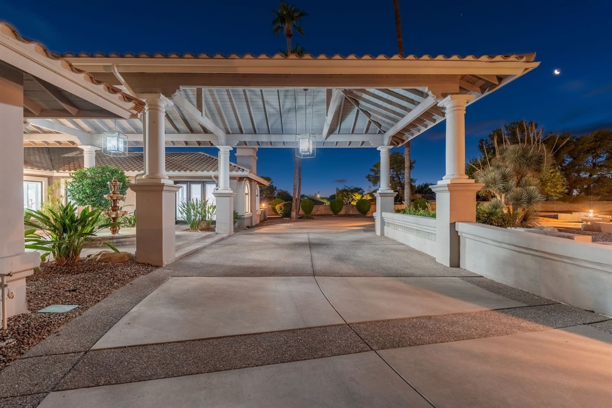 Enjoy the grandeur of a wide covered drive surrounded by desert landscaping and warm evening lights.

