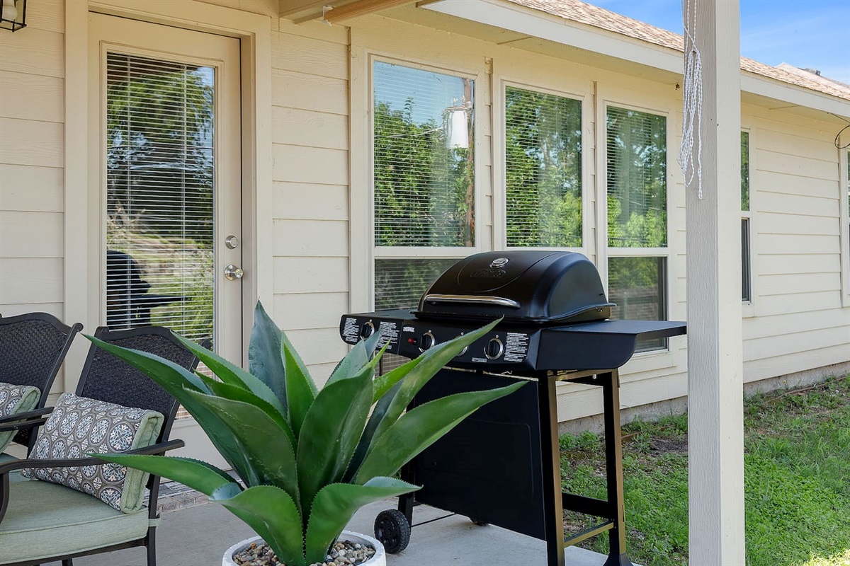Appreciate a cozy backyard patio with a barbecue grill and inviting seating arrangement.