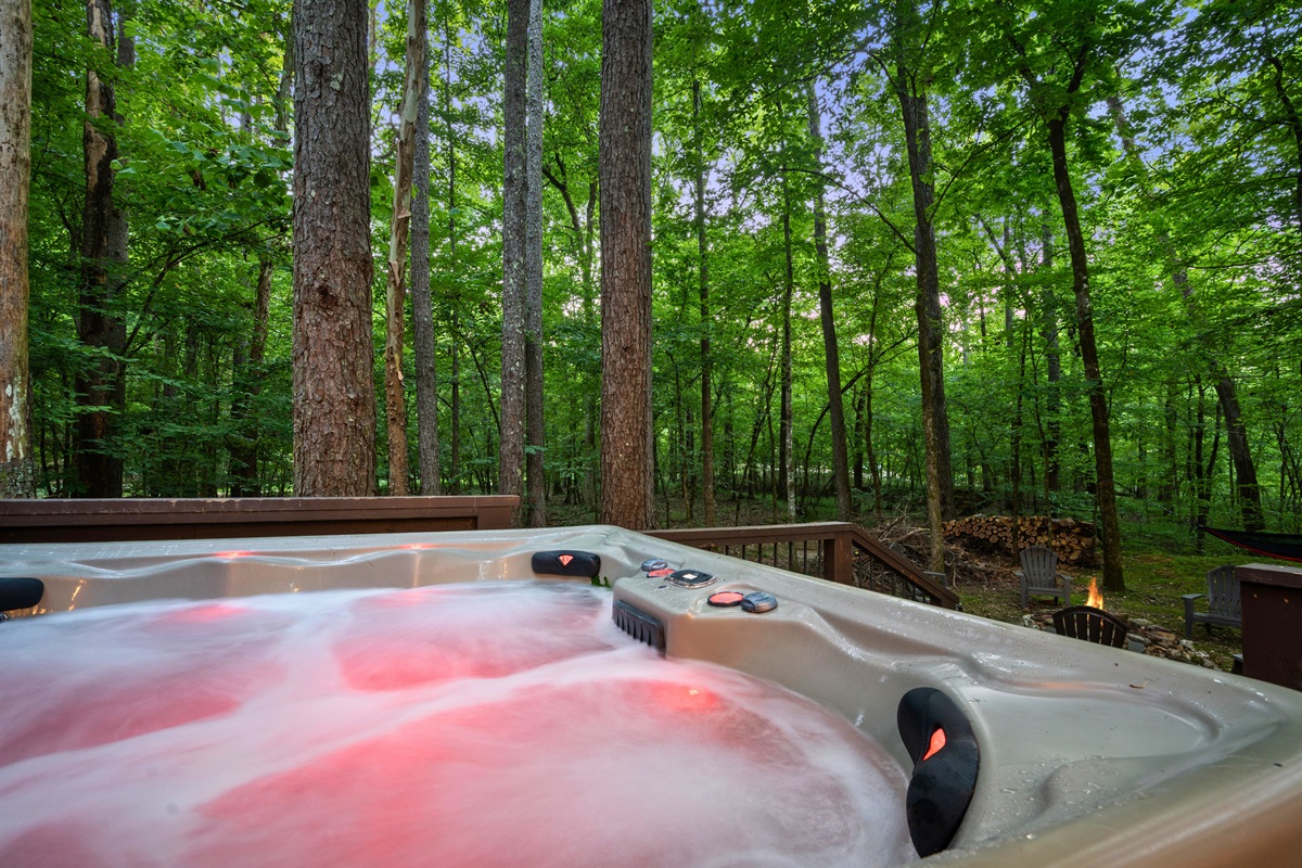 Soak and unwind in the bubbling hot tub surrounded by tall trees and peaceful forest views — the ultimate relaxation.