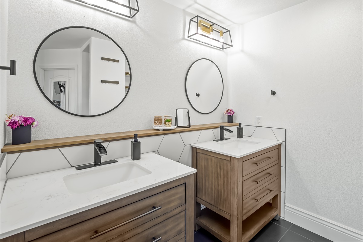Warm wood cabinetry, modern lighting, and sleek black fixtures create a polished, boutique-hotel feel with generous space to spread out.