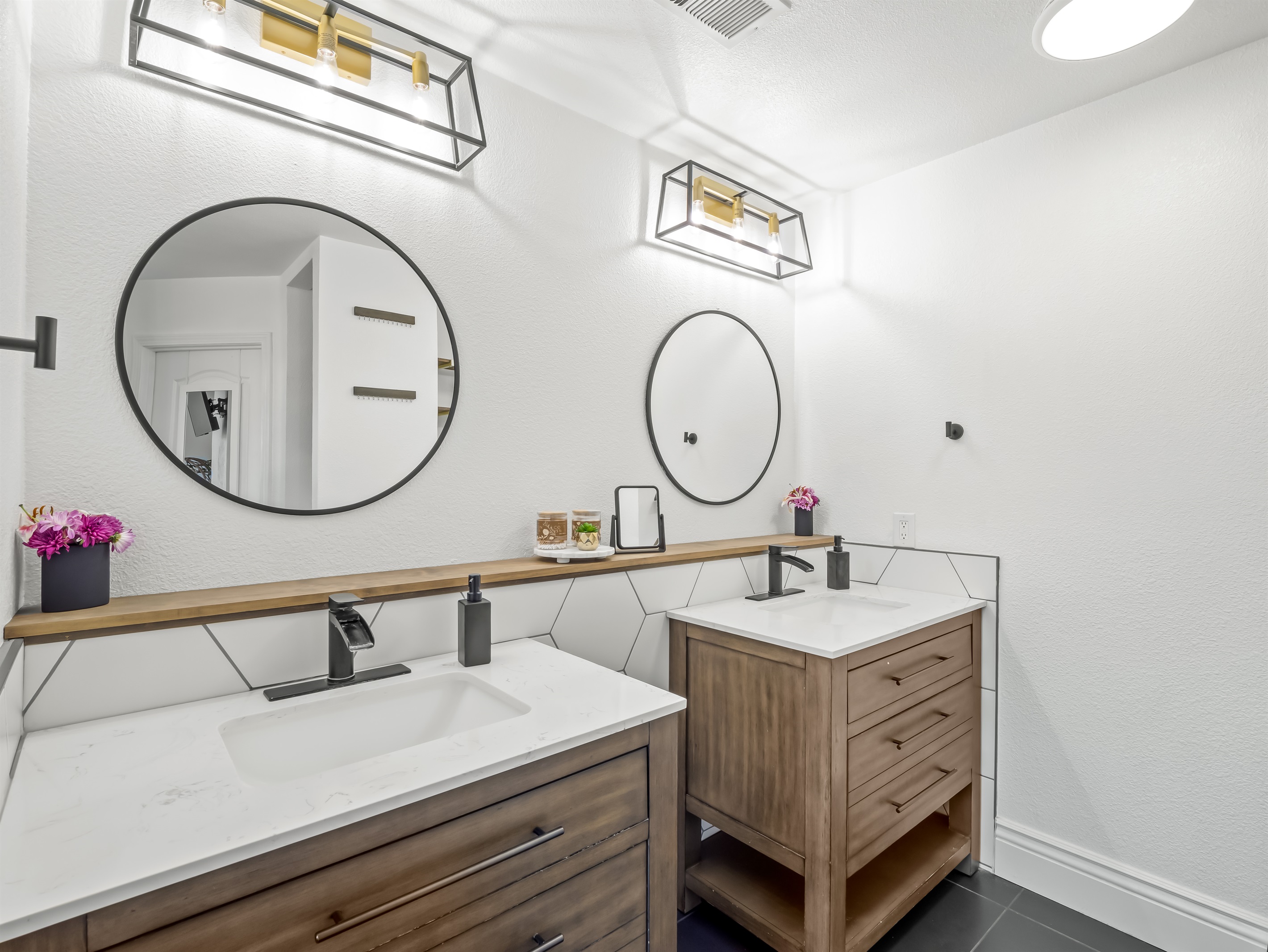 Warm wood cabinetry, modern lighting, and sleek black fixtures create a polished, boutique-hotel feel with generous space to spread out.