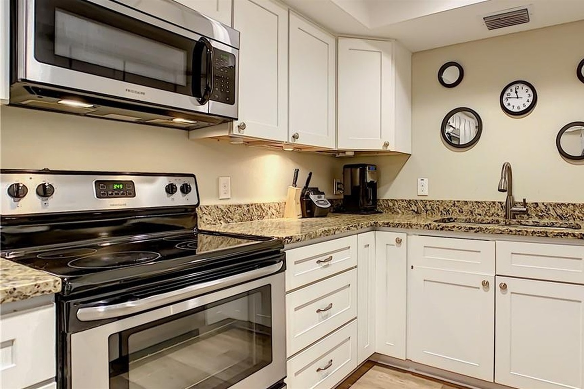 Modern kitchen with sleek black appliances, granite countertops and coffee maker—prepare meals and morning coffee before heading to Madeira Beach and John's Pass during your midterm stay in Seminole.