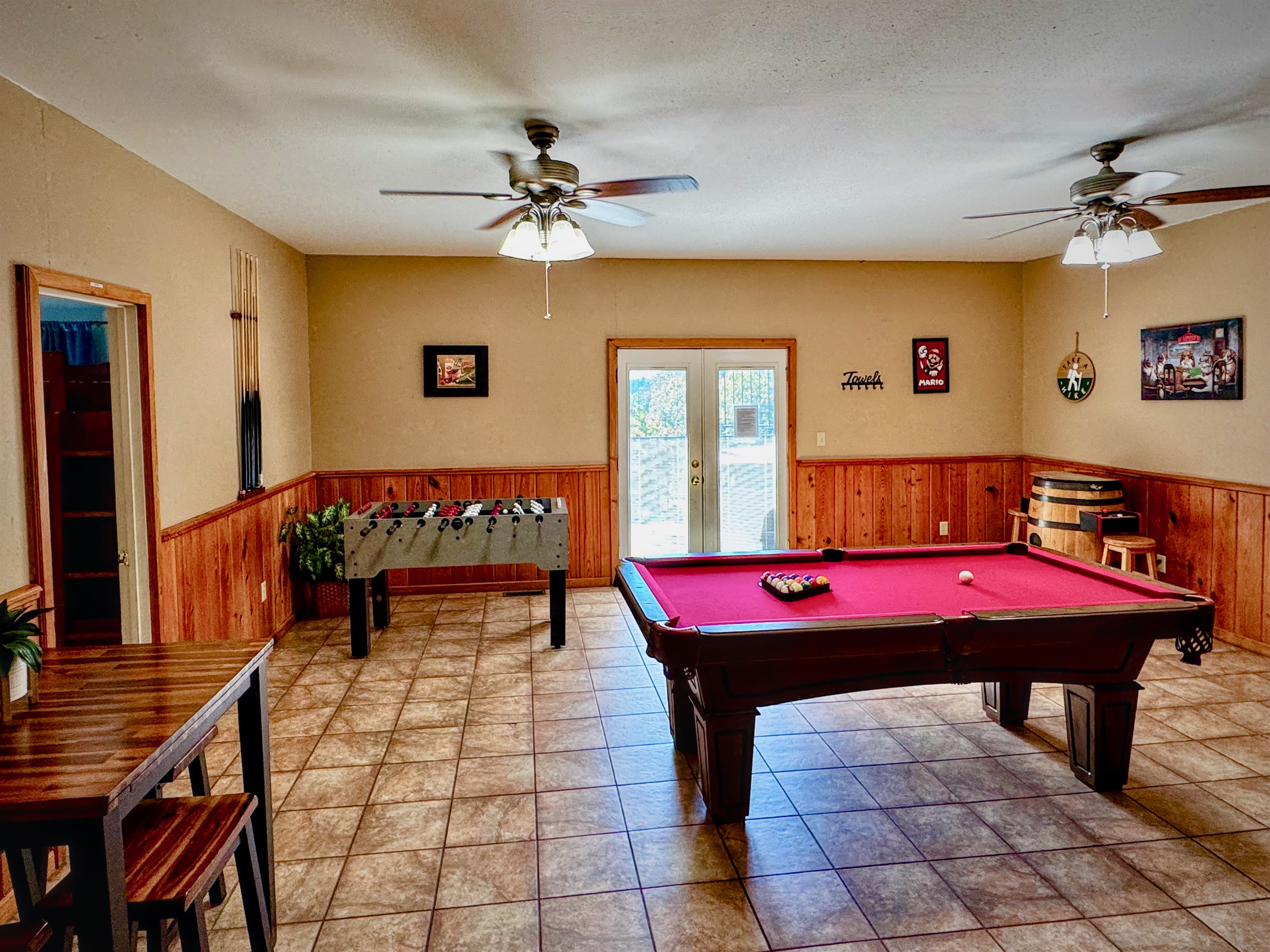 Game Room on mid-level with billiards, foosball, arcade table, large-screen TV, pub table, books, games, and French doors to access the lower-deck and hot tub.