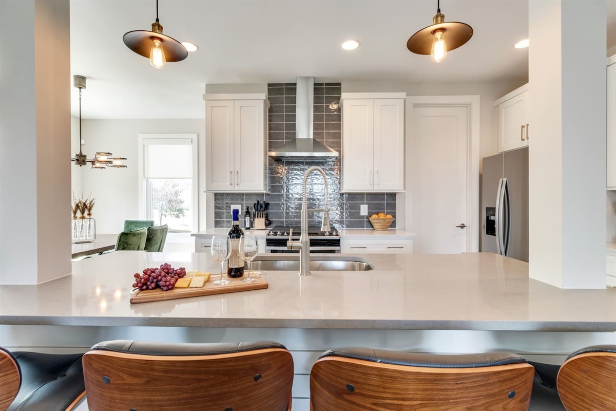 - Modern kitchen with quartz countertops, stainless steel appliances, and bold backsplash - Spacious island with seating, ideal for breakfast, wine nights, or work time - Warm pendant lights and curated finishes elevate the entire culinary space