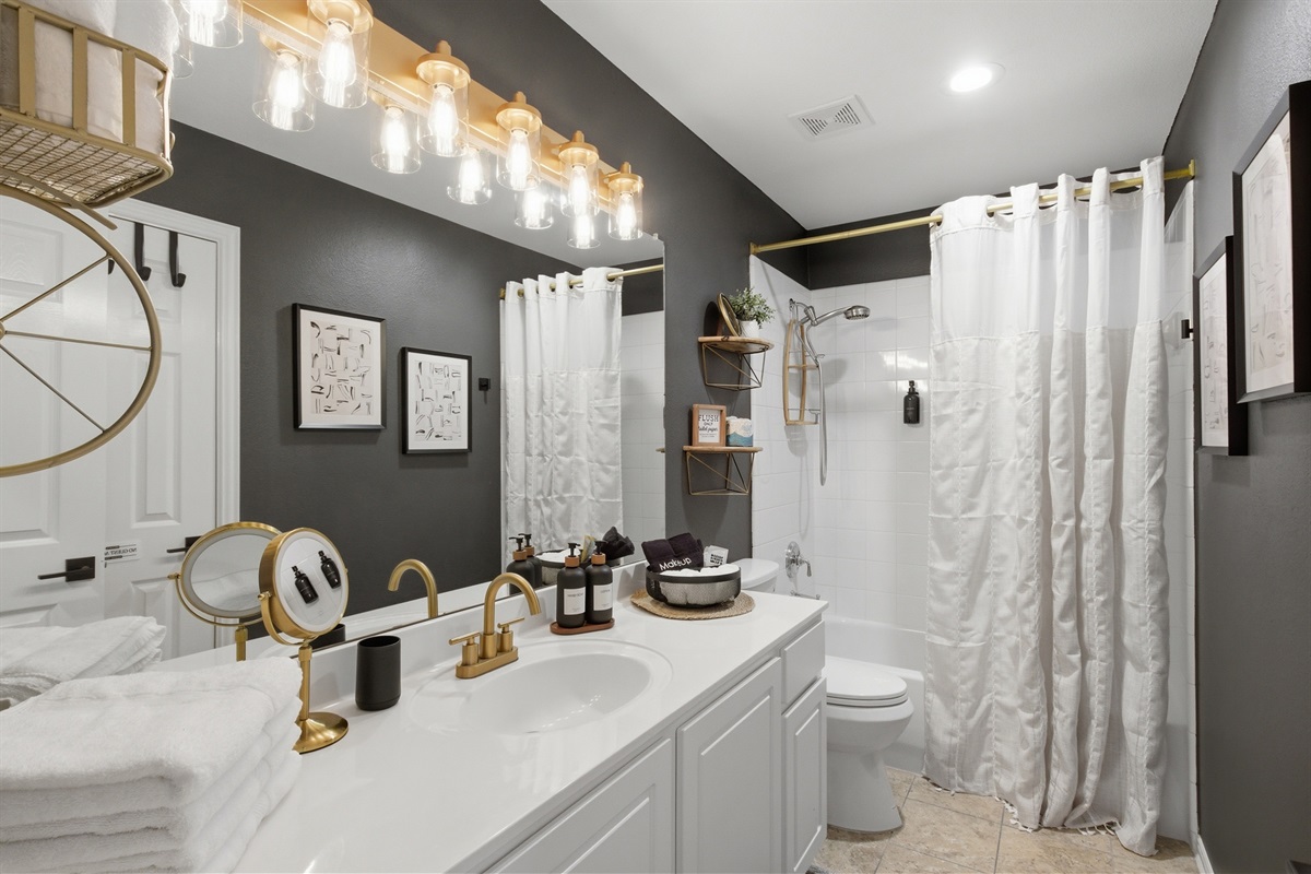 Guest Bathroom with a tub and shower combination, modern Vanity, and elegant gold fixtures. Stocked with essentials by Ginger Lily Farms.
