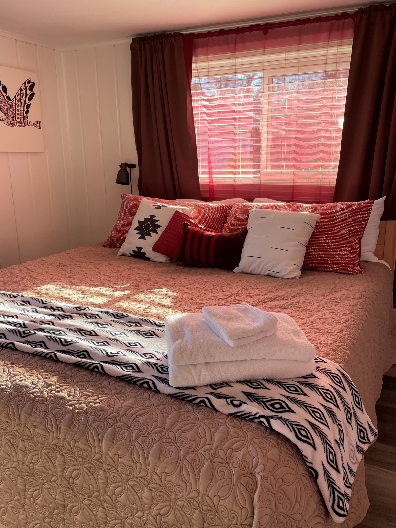The master bedroom features a king bed with patterned textiles and layered textures throughout. Curtains, bedding, and rug create a warm, inviting, and thoughtfully styled retreat.