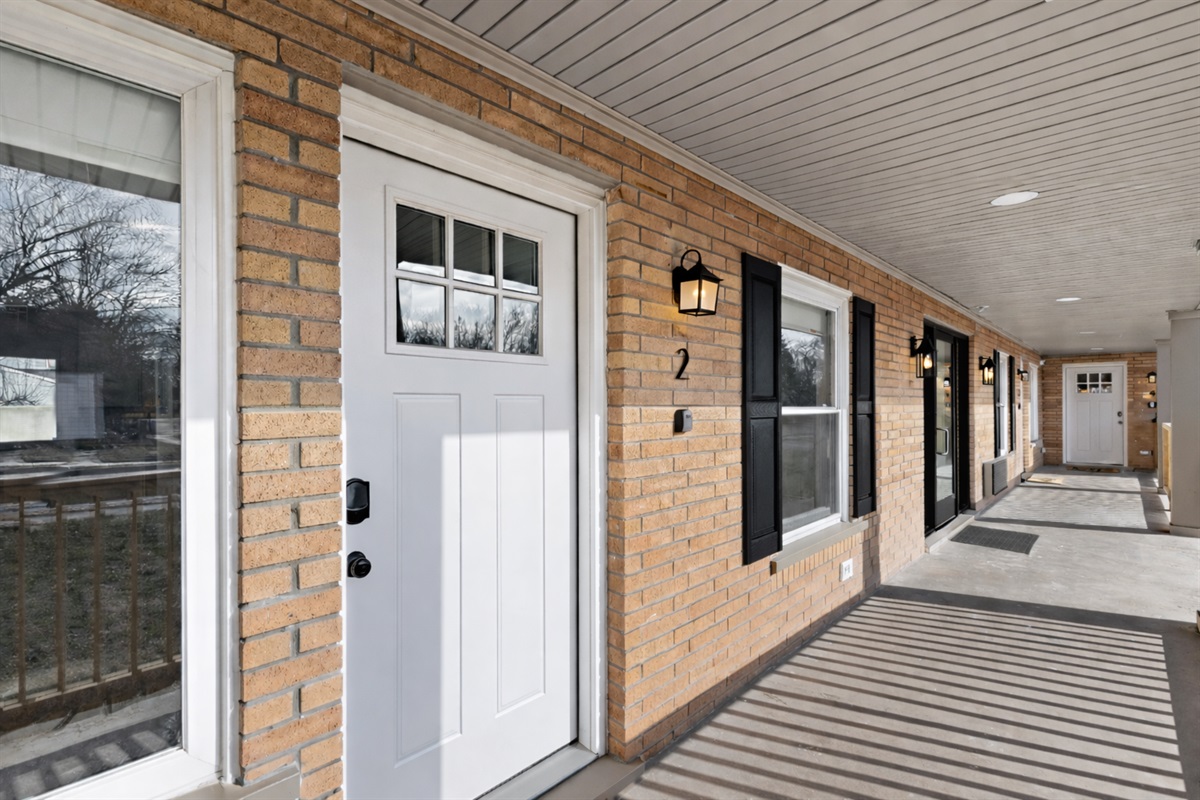 Inviting covered entry with a crisp white door, charming brick exterior, and soft lighting—offering a warm, private welcome from the moment you arrive.