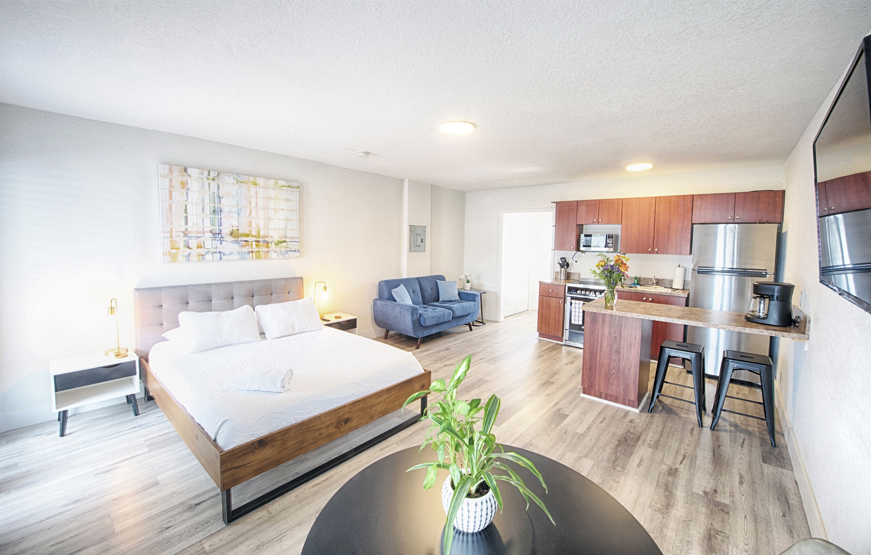 Wide view of open concept bedroom with with kitchen and love seat accent chair.