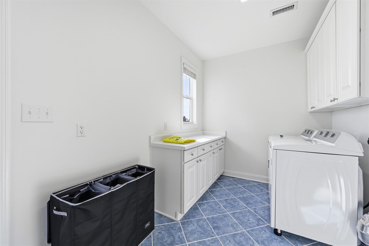 Spacious laundry area with folding counter, laundry hamper, and everything needed for longer stays