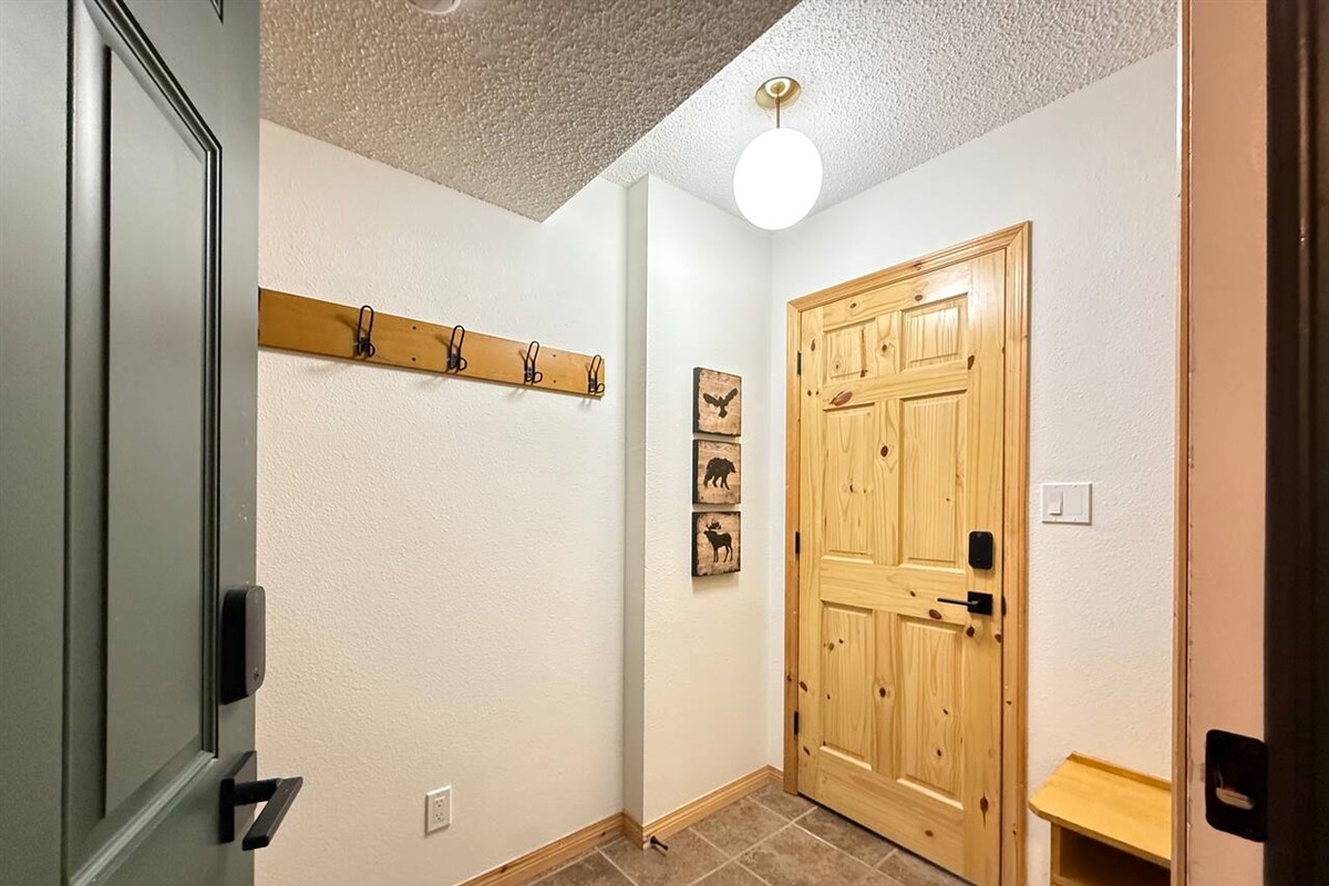 Efficient Entryway Storage: Compact and functional entrance at the Kimberley townhouse, featuring a wooden coat rack with ample hooks and floor space for boots.