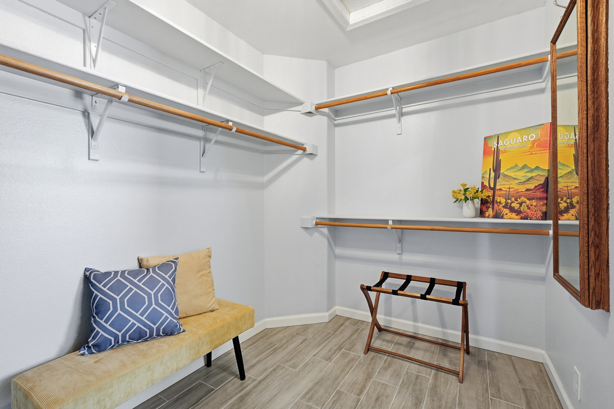 Walk-in closet with open shelving, hanging space, fresh towels, and a bench for easy unpacking during your stay.