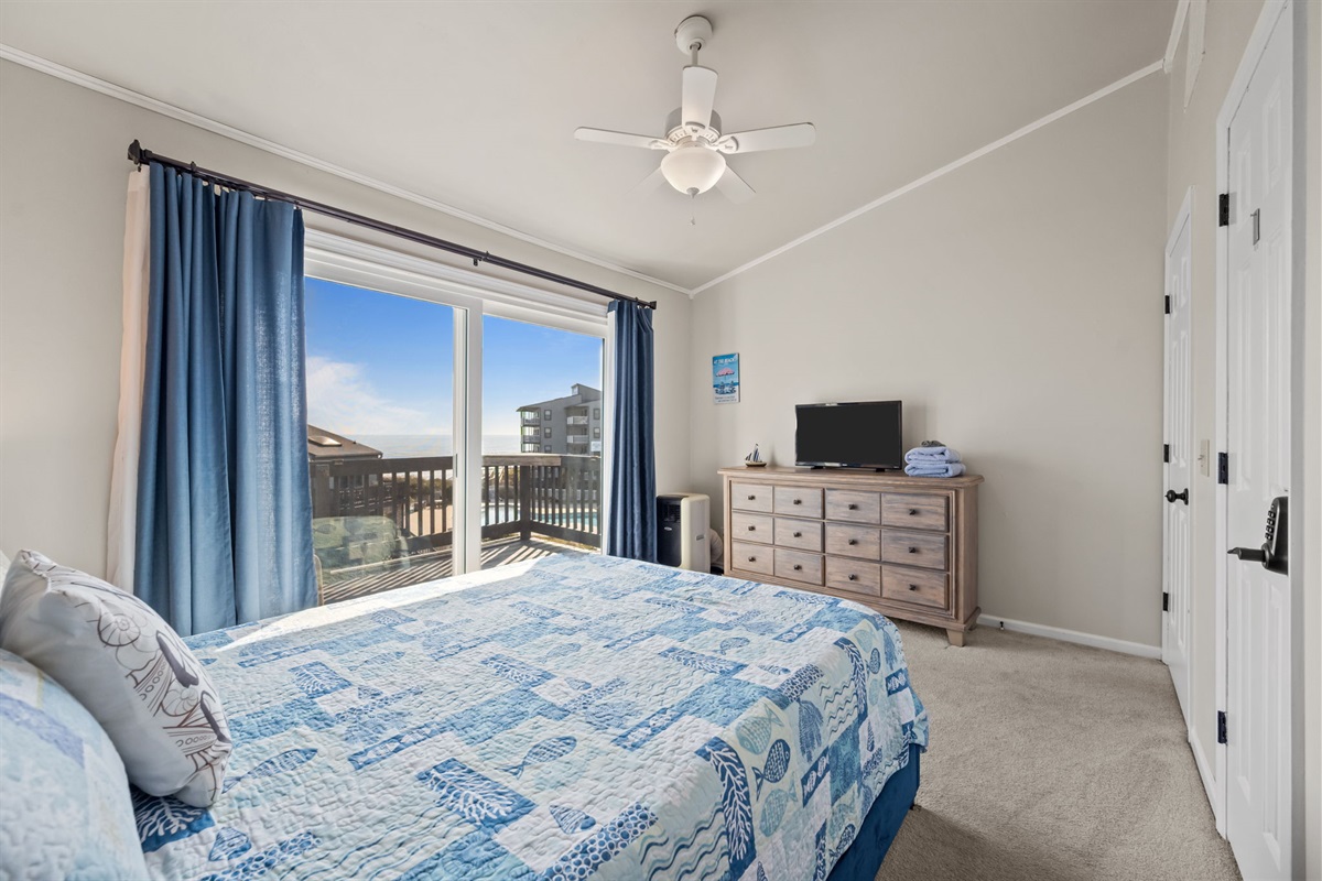 Spacious master bedroom with TV, dresser, and direct access to the balcony for fresh ocean breezes