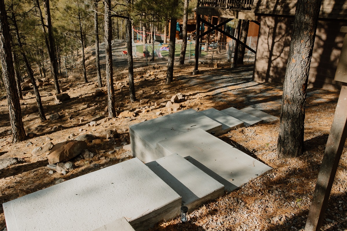 Thoughtfully positioned concrete steps guide you seamlessly through the wooded terrain, connecting upper and lower levels of the property. These sturdy pathways make exploring the grounds effortless, ensuring safe access to all outdoor living spaces.