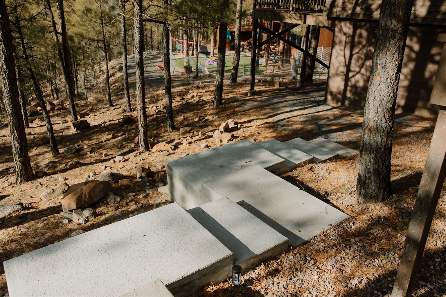 Thoughtfully positioned concrete steps guide you seamlessly through the wooded terrain, connecting upper and lower levels of the property. These sturdy pathways make exploring the grounds effortless, ensuring safe access to all outdoor living spaces.