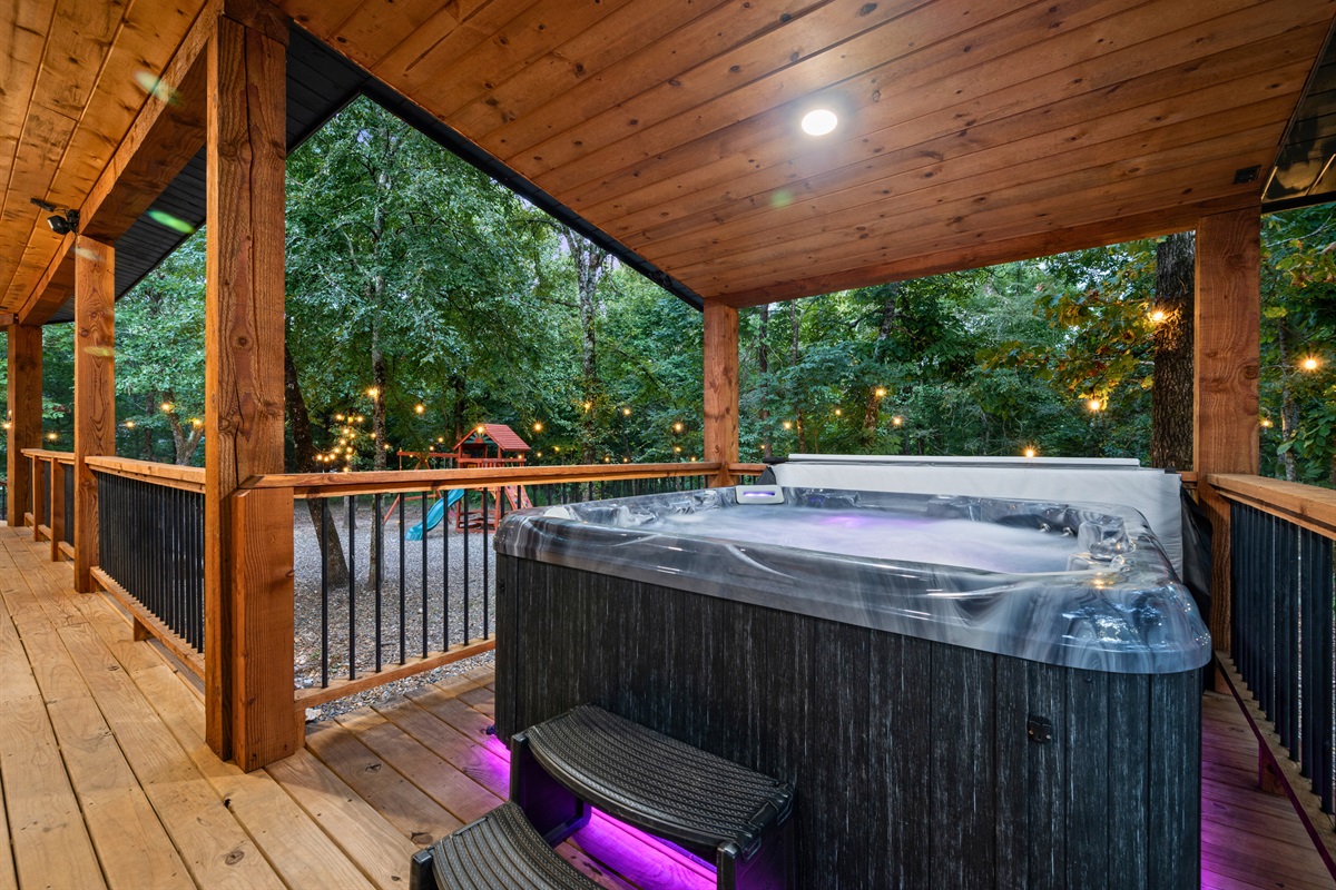 Unwind in the private hot tub with a wooded backdrop and outdoor seating area.
