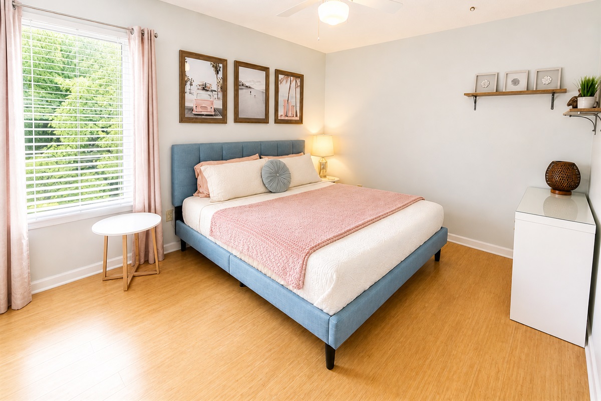 Pink room with writing desk, television, and king size bed 