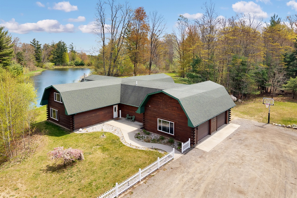 Aerial view of the home entry, garage, parking, pond and basketball hoop.