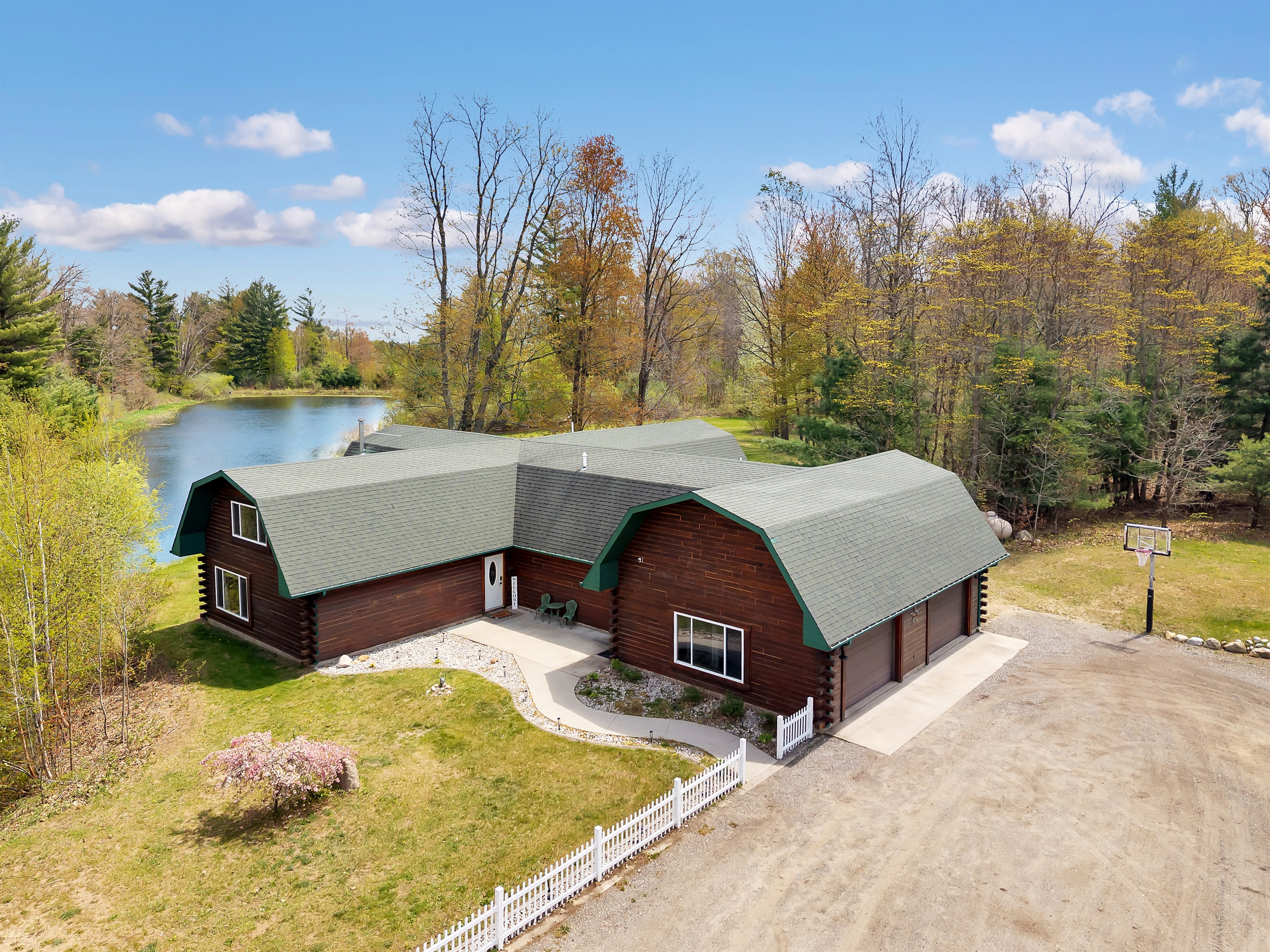 Aerial view of the home entry, garage, parking, pond and basketball hoop.