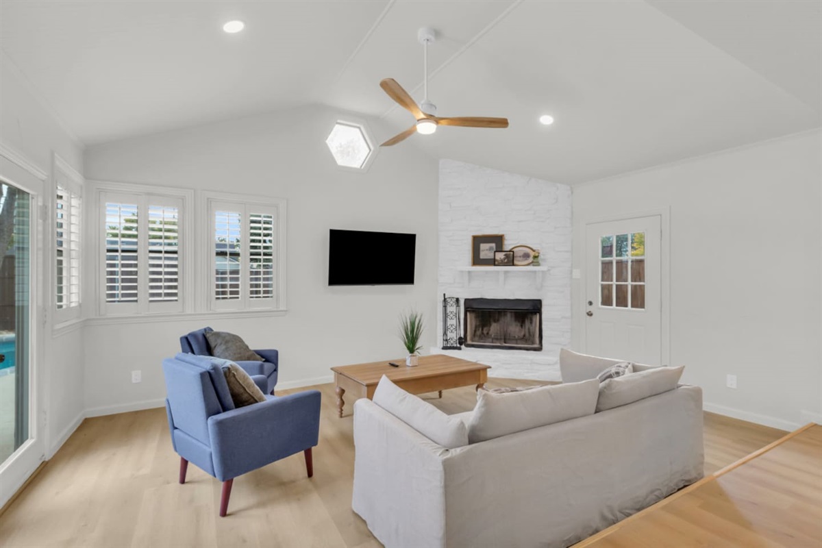 Cozy private living room with comfortable seating, large TV, and plenty of natural light. Stay cool with air conditioning and a modern ceiling fan.