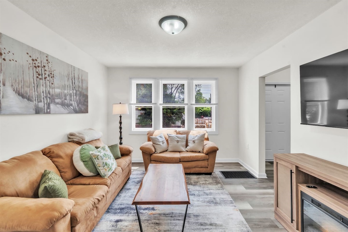 Enjoy a relaxing atmosphere in the living room with comfortable couches, natural light from the large window, and a TV for your leisure.
