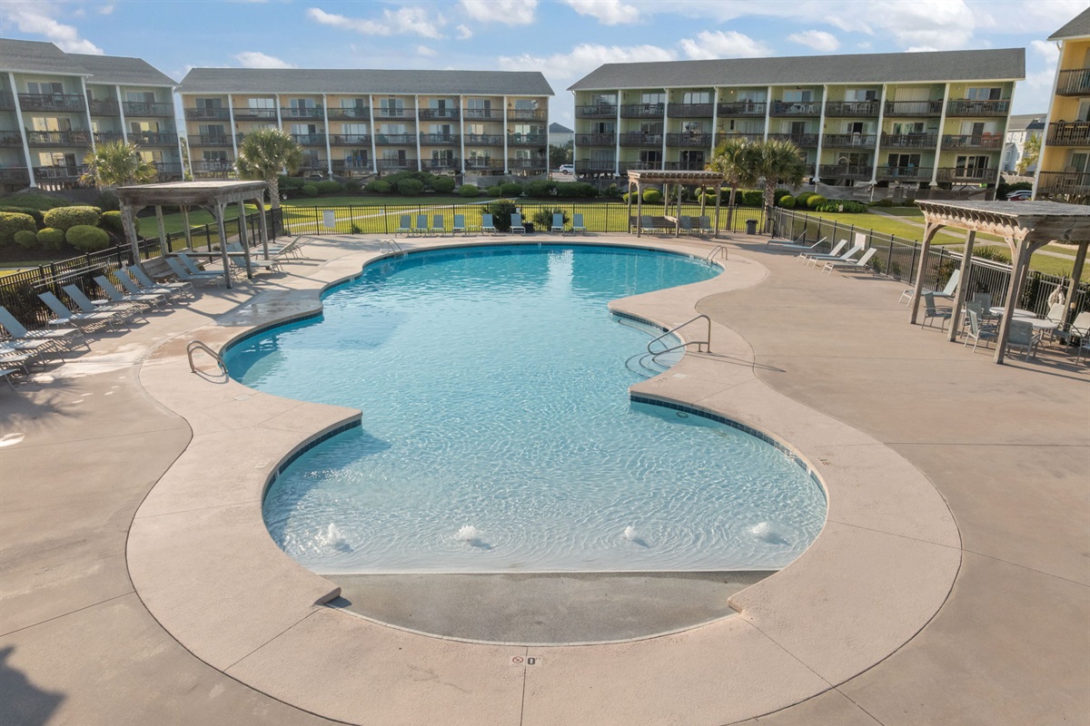 Spacious community pool with lounge areas for relaxing in the sun
