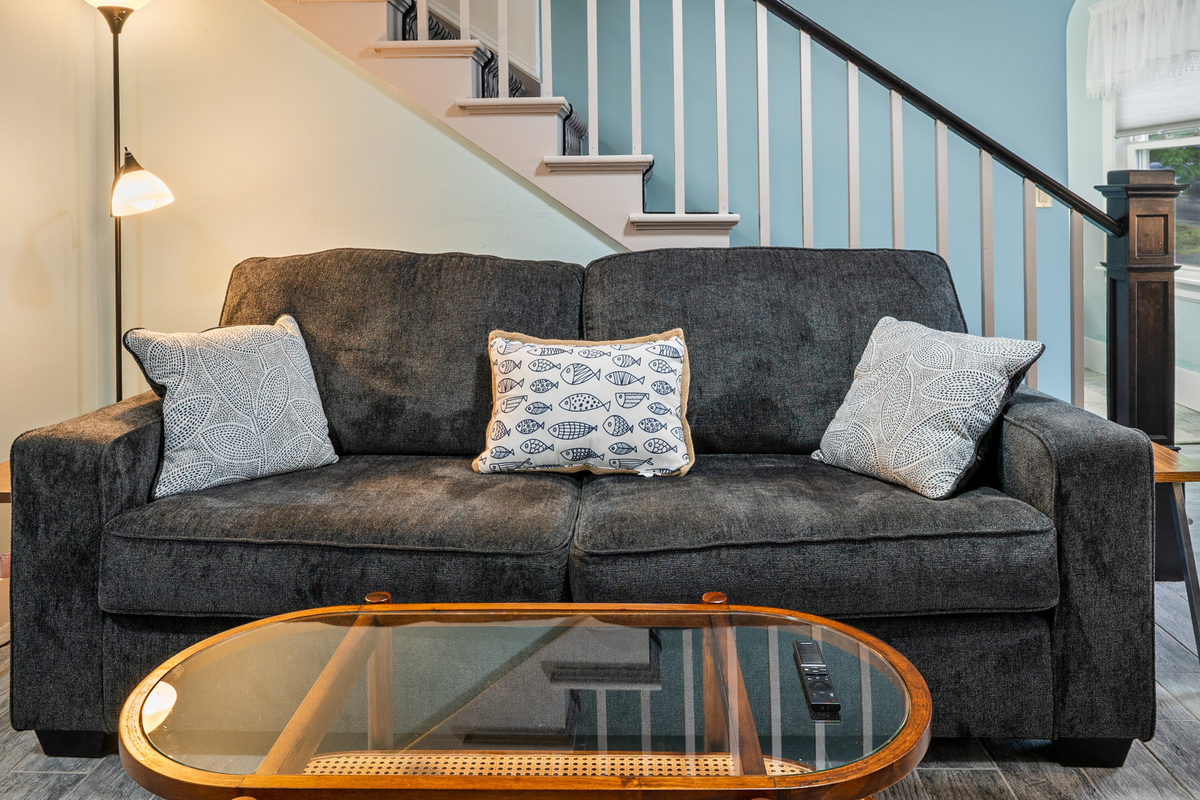 Settle into the deep charcoal couch for an evening of entertainment. Positioned perfectly near the reading lamp and featuring a glass-top coffee table for your snacks and remotes, this central living room spot is built for your group's relaxation.