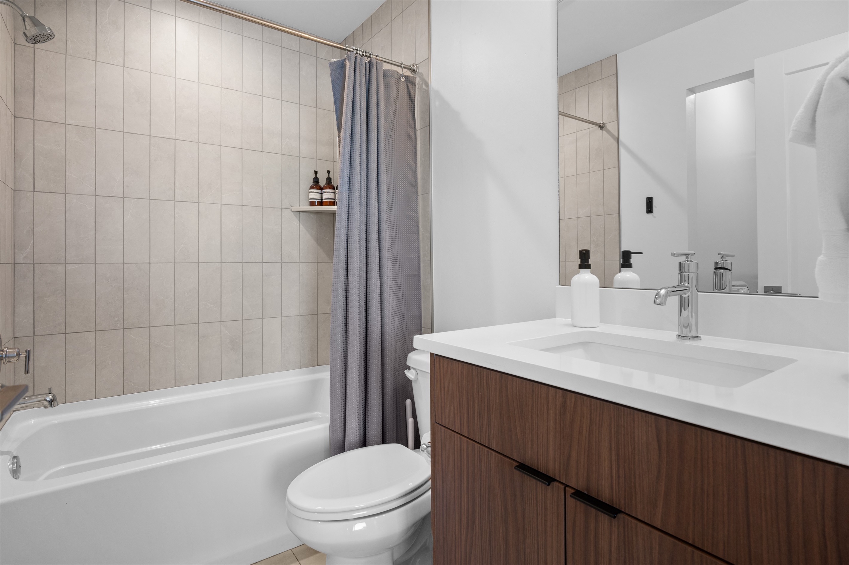 Contemporary full bath with tile surround and sleek finishes.