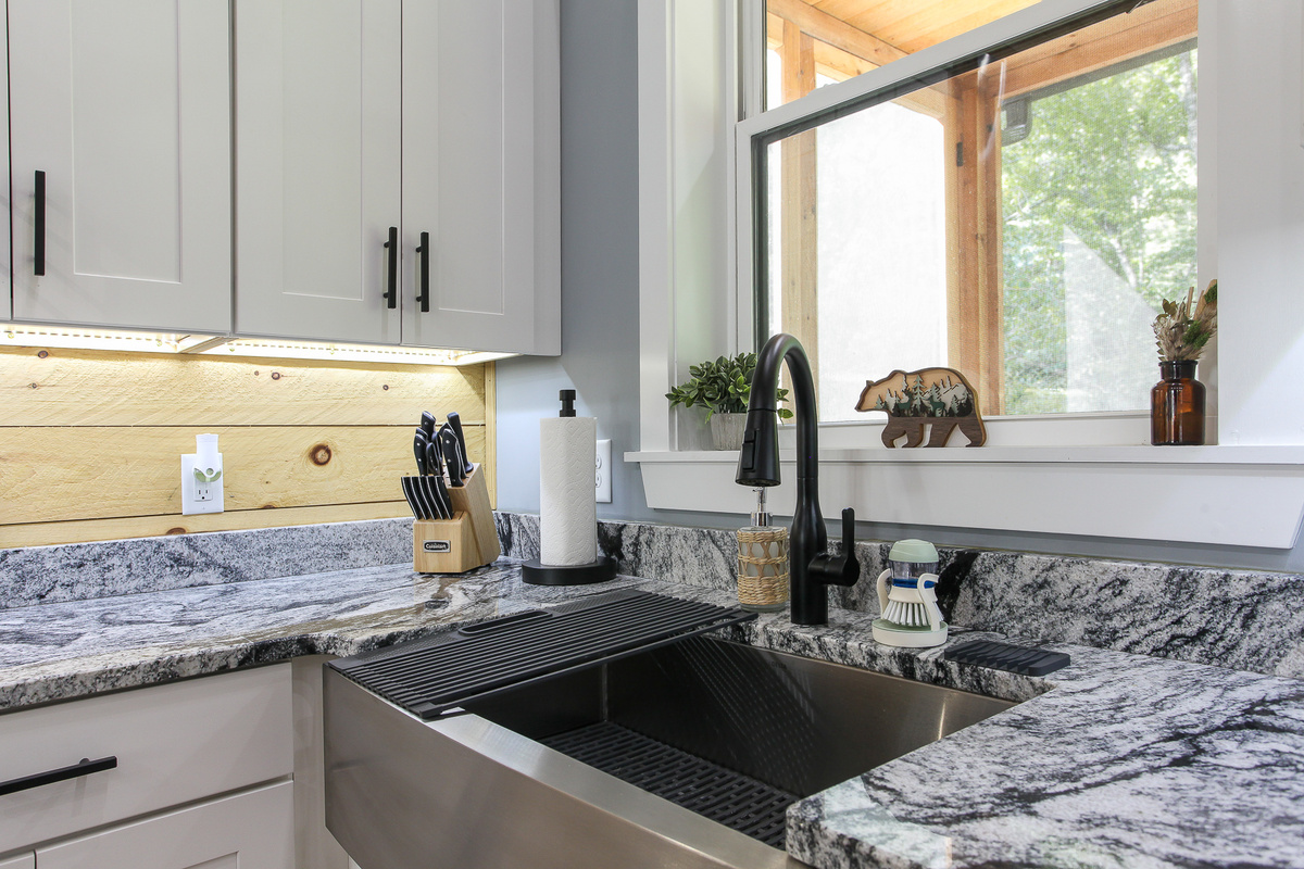 A spacious farmhouse sink beneath the window brings natural light and a view of the trees to the kitchen at Robbin’s Nest on Snowbird Creek.