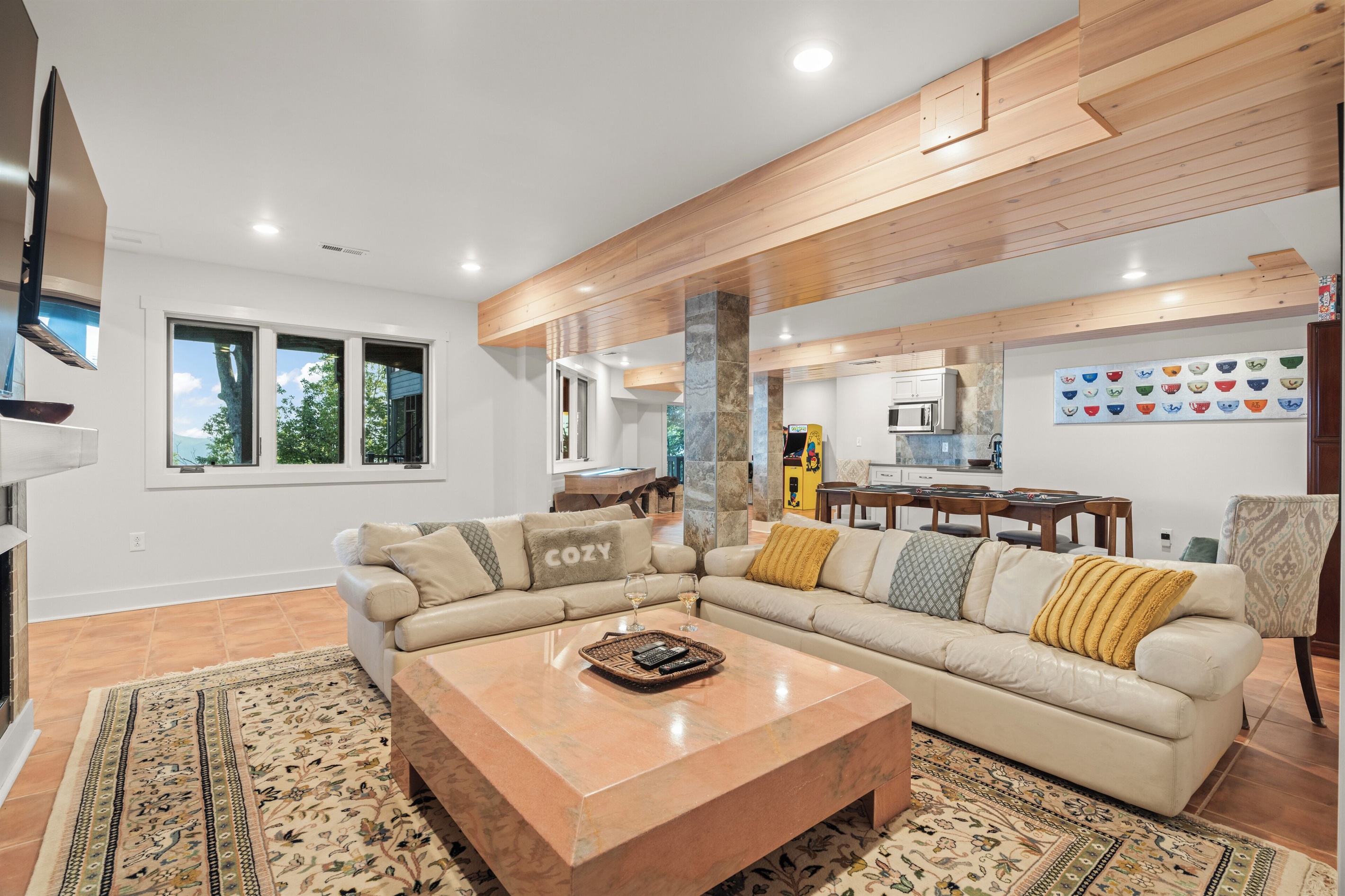 Downstairs rec room with multiple TVs, kitchenette, shuffeboard, and arcades