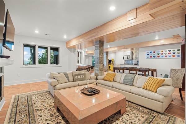 Downstairs rec room with multiple TVs, kitchenette, shuffeboard, and arcades