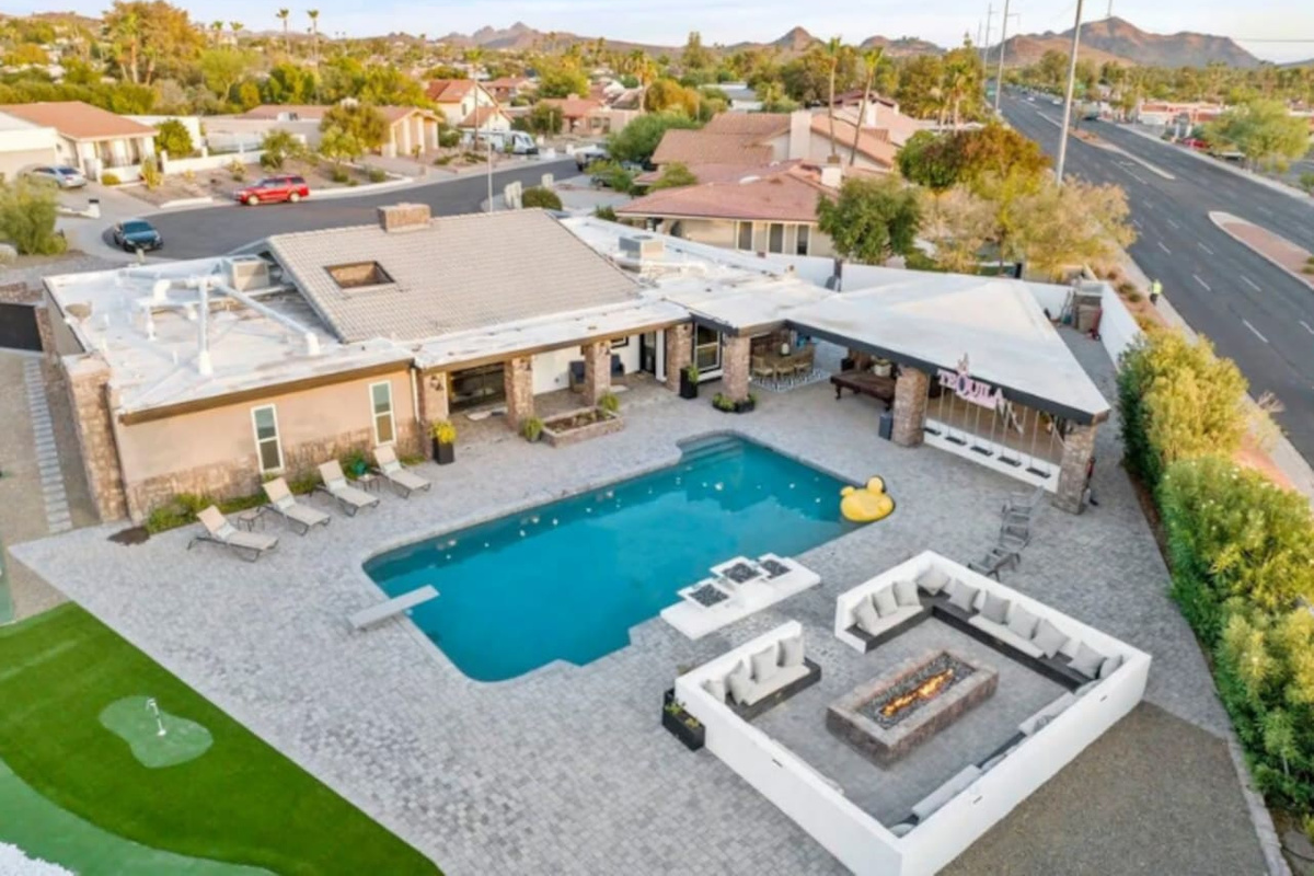 An aerial view reveals it all — pool, putting green, fire pit lounge, and mountain views in one incredible backyard.