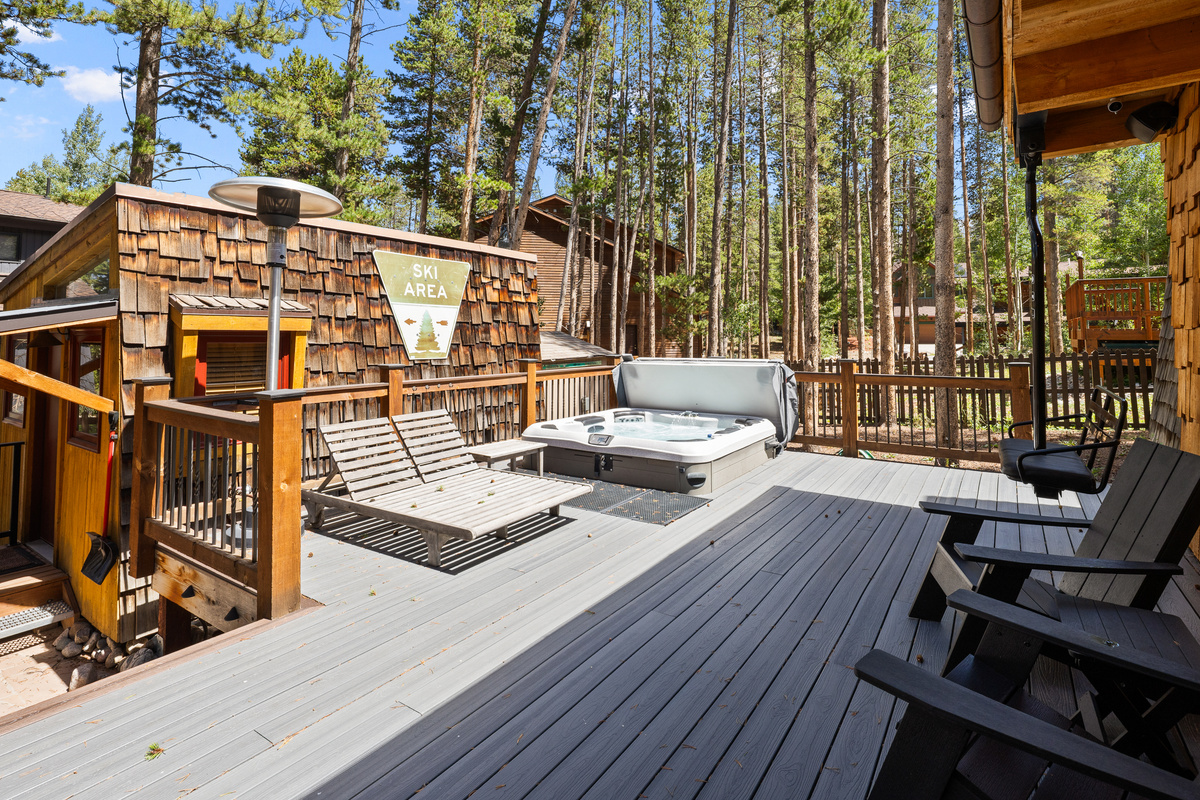 Rear deck off living area with lounge seating, chairlift swing, in-ground hot tub and the bungalow seen on left. 