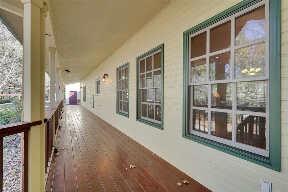 Covered porch view with wood flooring, screened windows, and a quiet walkway along the home.
