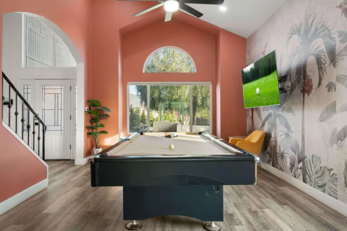 Game room with pool table, coral accent walls, botanical wallpaper, and floor-to-ceiling views.