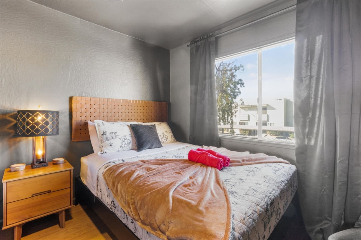 Queen bedroom with soft bedding, bedside lighting, and a calm place to rest.