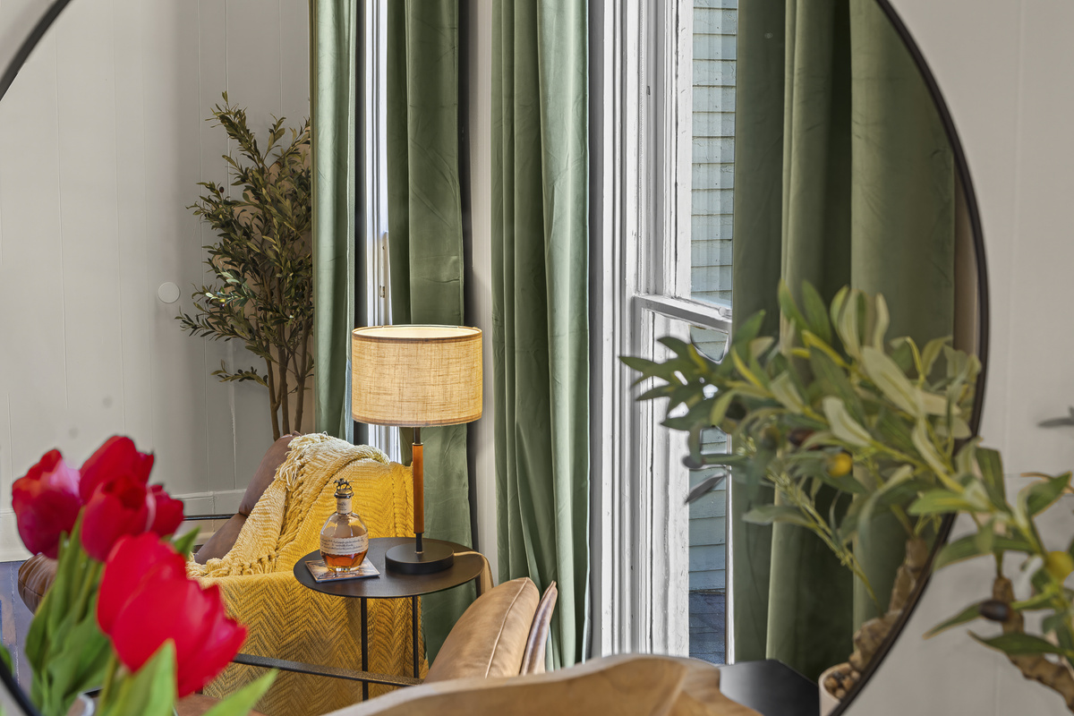 A round mirror, red tulips, and a leather chair in the corner.