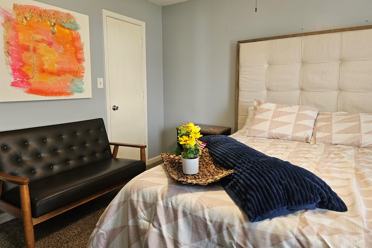 Queen primary bedroom with extra seating, ceiling fan, fast WIFI, TV, ensuite bathroom, and walk-in closet. Big window overlooking the fenced back yard adds fresh natural light and appeal.