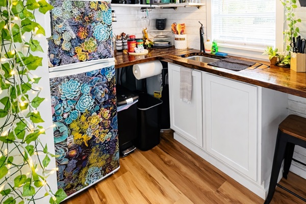 A warm and inviting kitchen with soft lighting and charming touches — lighted vines drape gently along open shelves, casting a cozy glow over the rustic wood countertop