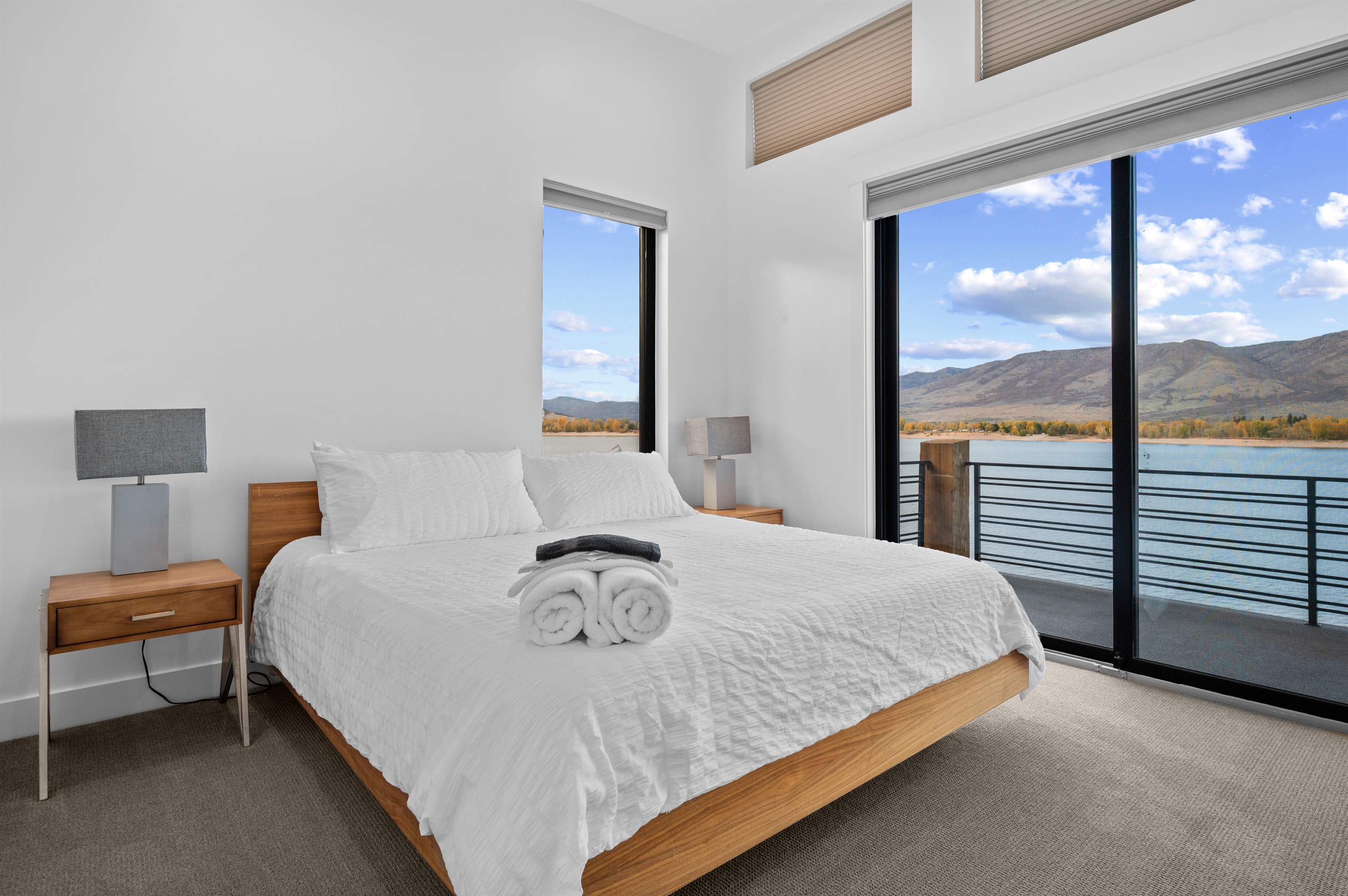 King bedroom with floor-to-ceiling windows and direct balcony access overlooking Pineview Reservoir.