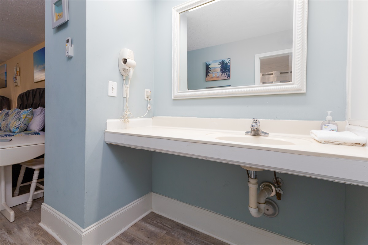Vanity area with spacious counter, mirror, and hair dryer&mdash;perfect for getting ready after a beach day