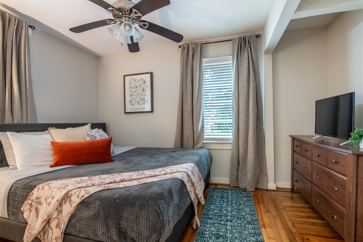 Comfortable queen bedroom with bold accent pillows, ample windows, and modern furnishings.