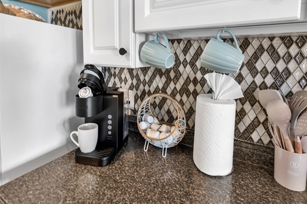 Kitchen counter with Keurig, mugs, paper towels, and cooking utensils — all the essentials ready to use