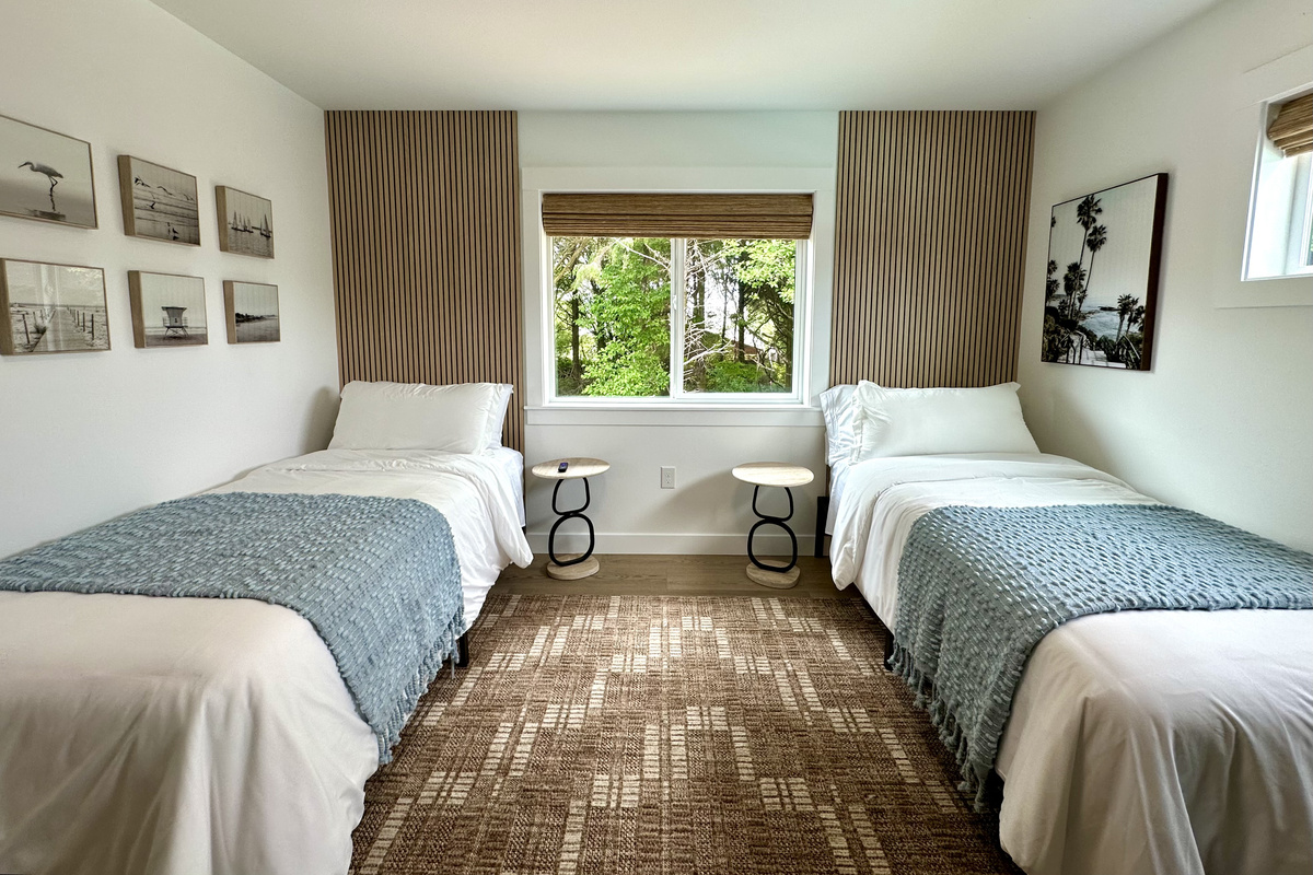 Two twin beds under coastal art — an easy room for kids, or for friends who'd rather not share.