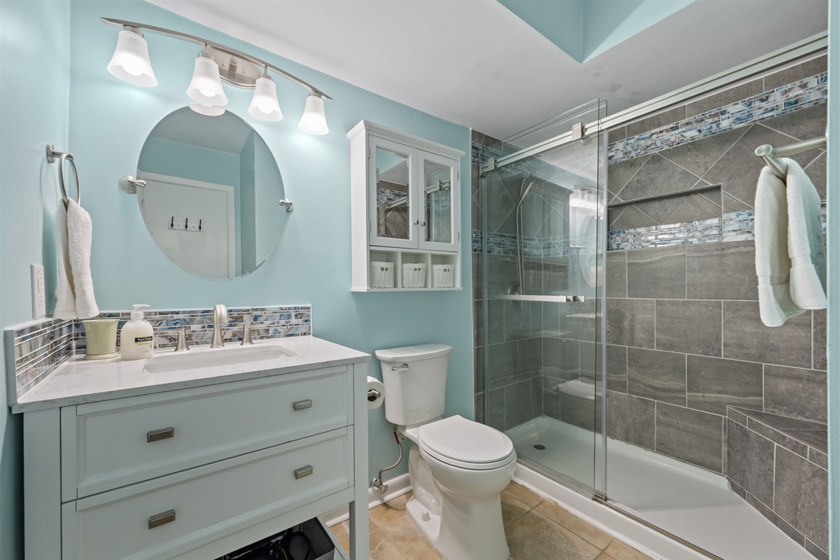 Bright Master bathroom featuring a glass-enclosed shower, contemporary vanity, and fresh coastal finishes.
