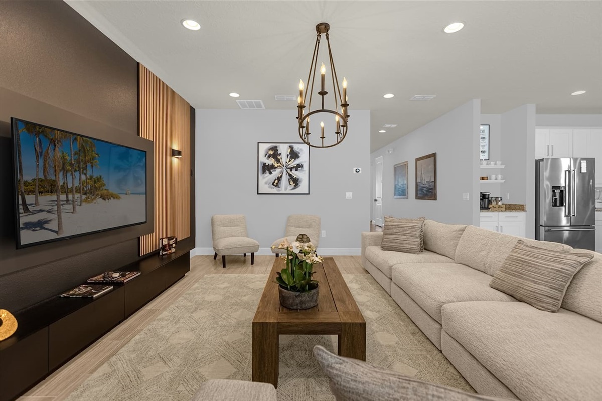 From another angle, the living room reveals its airy layout, with a sleek sofa facing the smart TV and a chic coffee table in the center. Large windows bring in ample sunlight, highlighting the room’s modern décor and inviting atmosphere.