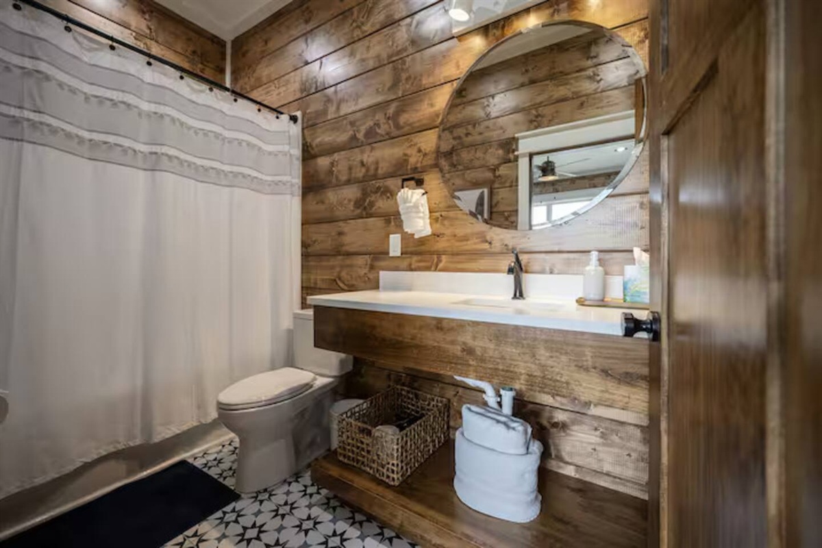 Bathroom with shower-tub combo and rustic wood interior.