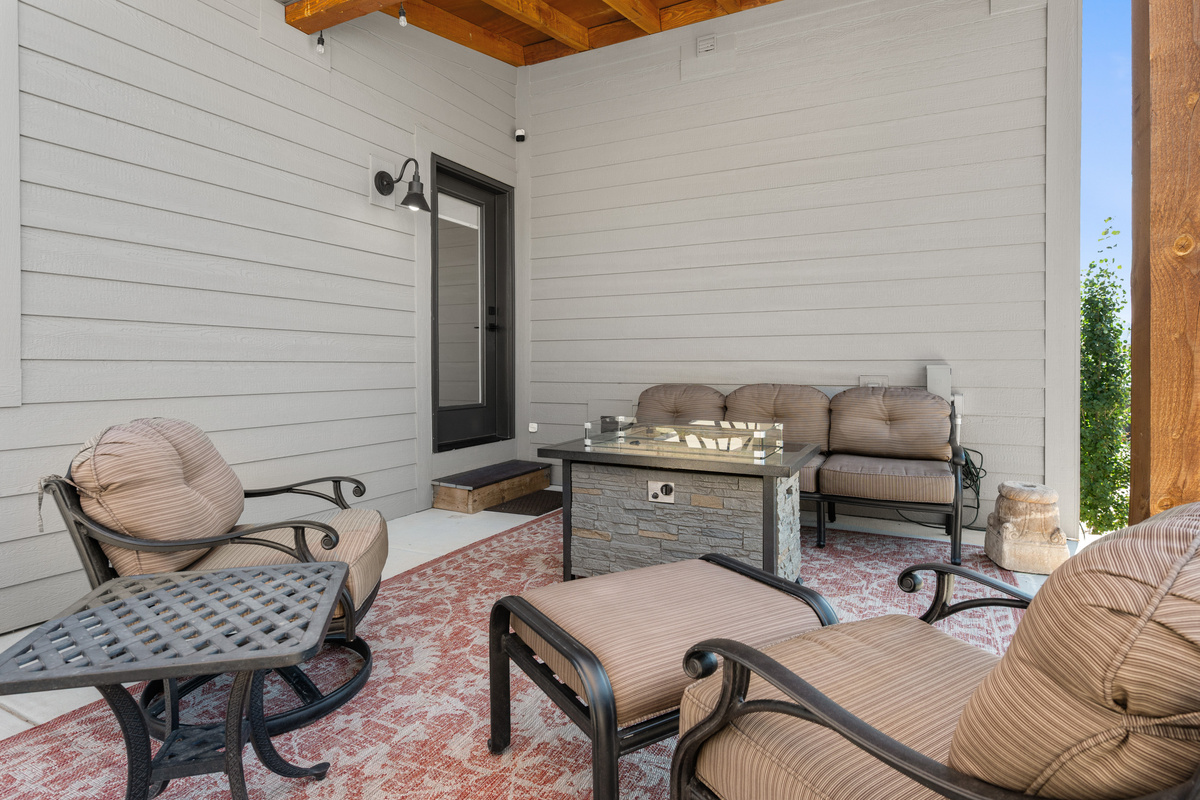 Covered outdoor living area with comfortable seating and a fire table—perfect for gathering with family and friends year-round.